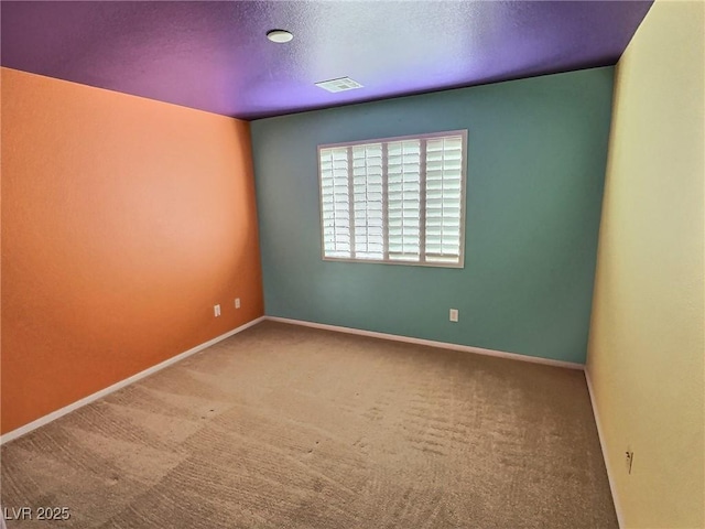 carpeted spare room featuring visible vents, baseboards, and a textured ceiling