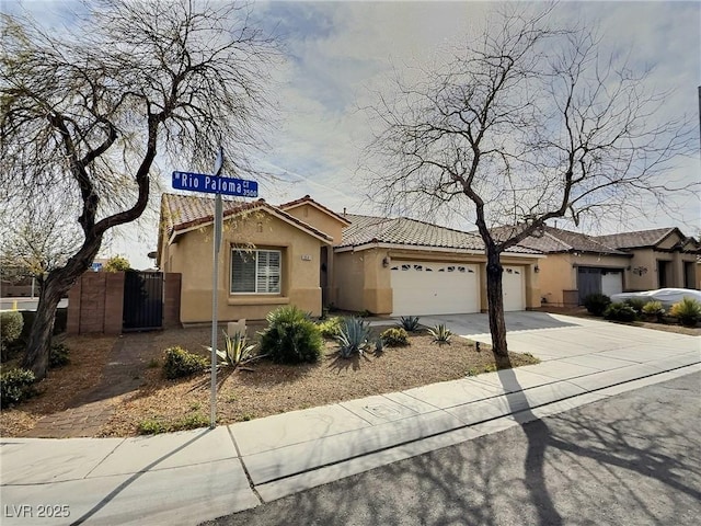 view of front of property with concrete driveway, a tiled roof, an attached garage, and stucco siding