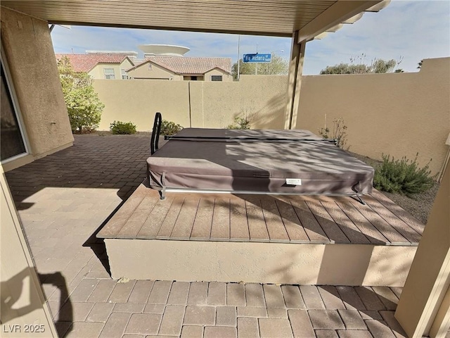 view of patio featuring a covered hot tub and fence