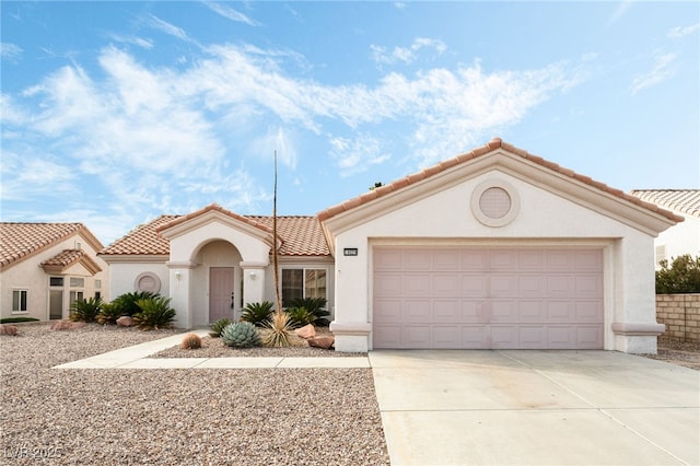 mediterranean / spanish house with an attached garage, driveway, a tile roof, and stucco siding