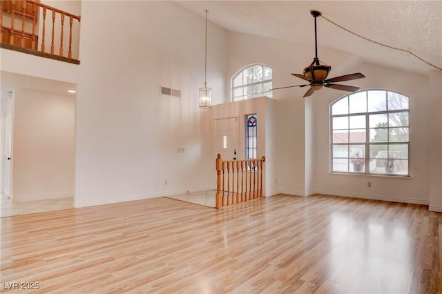 spare room featuring ceiling fan, high vaulted ceiling, visible vents, baseboards, and light wood finished floors