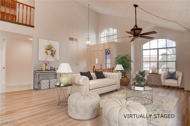 living room featuring ceiling fan, vaulted ceiling, wood finished floors, and visible vents