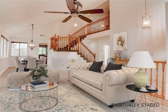 living area featuring high vaulted ceiling, stairway, baseboards, and an inviting chandelier