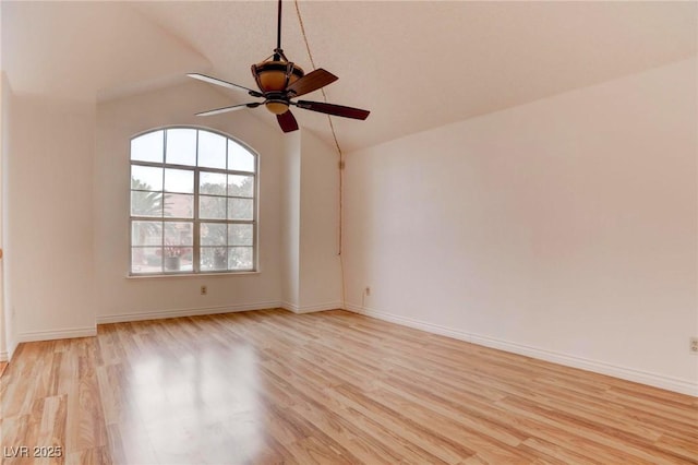 empty room featuring lofted ceiling, light wood-type flooring, a ceiling fan, and baseboards