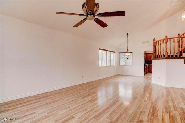 unfurnished living room featuring vaulted ceiling, ceiling fan with notable chandelier, light wood-style flooring, and baseboards