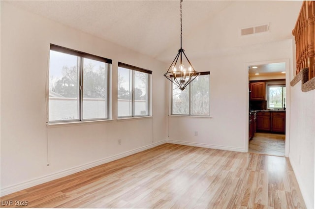 unfurnished dining area with light wood-style floors, visible vents, baseboards, and an inviting chandelier