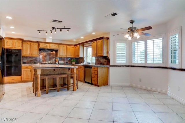 kitchen featuring dobule oven black, a sink, visible vents, stainless steel dishwasher, and tasteful backsplash