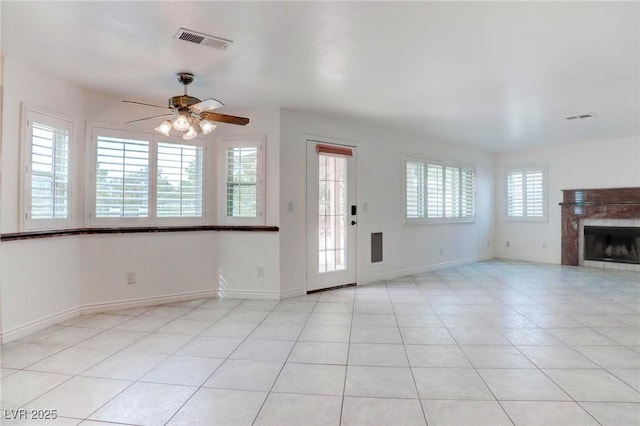 interior space with a tile fireplace, visible vents, baseboards, and light tile patterned floors