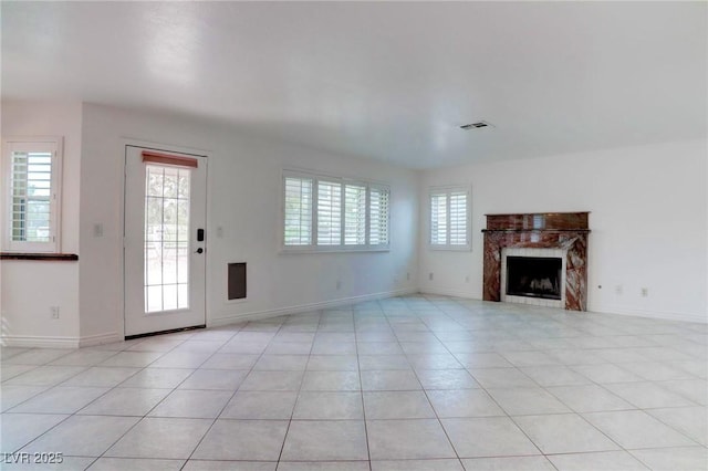 unfurnished living room featuring a tile fireplace, visible vents, baseboards, and light tile patterned floors