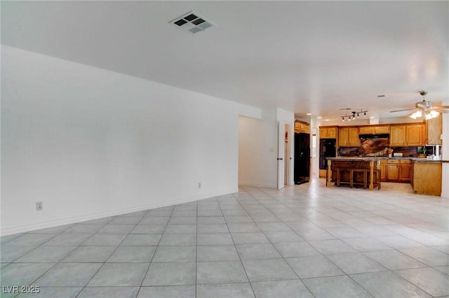 unfurnished living room featuring a ceiling fan, visible vents, baseboards, and light tile patterned floors