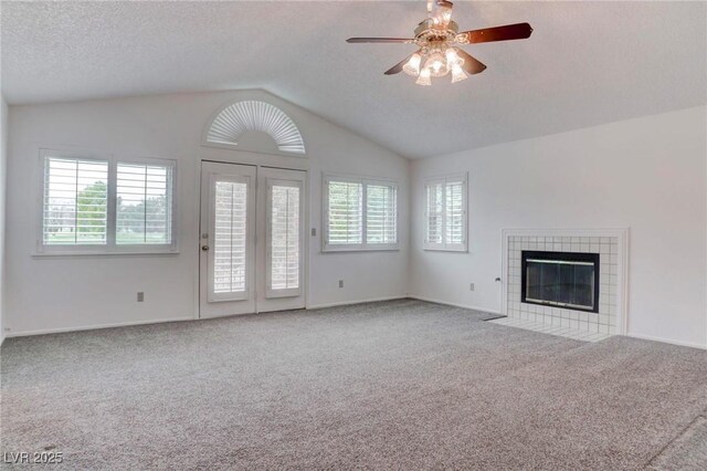 unfurnished living room with carpet, vaulted ceiling, a fireplace, and plenty of natural light