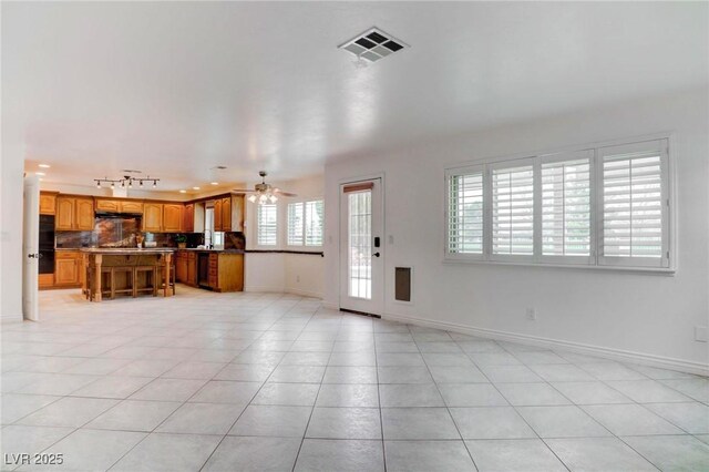 unfurnished living room featuring light tile patterned floors, rail lighting, visible vents, a ceiling fan, and baseboards