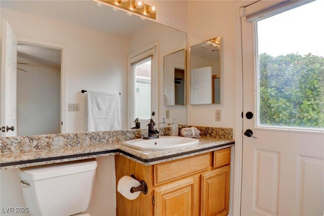 bathroom with a healthy amount of sunlight, vanity, and toilet