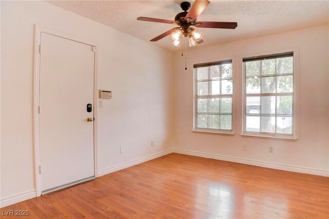 unfurnished room featuring ceiling fan, a textured ceiling, baseboards, and wood finished floors