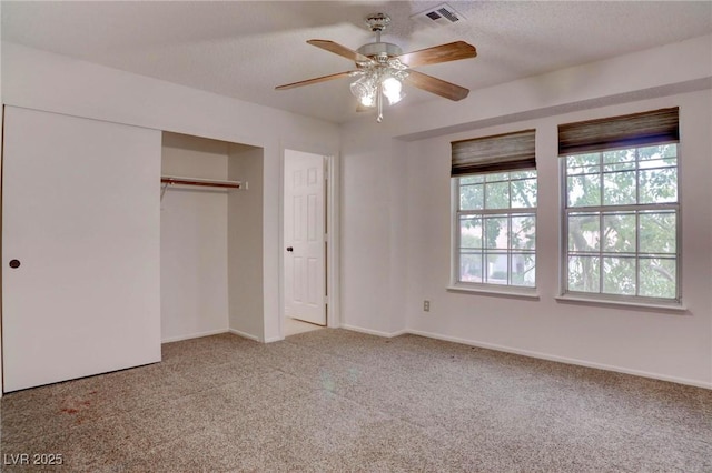 unfurnished bedroom with baseboards, visible vents, ceiling fan, carpet, and a closet