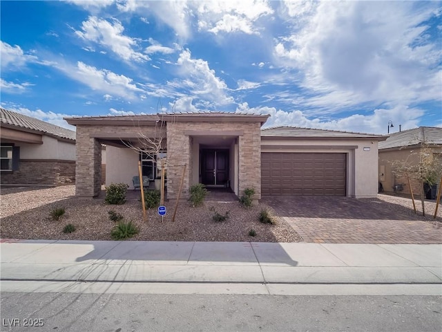 view of front of property featuring an attached garage, decorative driveway, and stucco siding