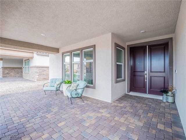 doorway to property featuring stone siding, a patio, and stucco siding