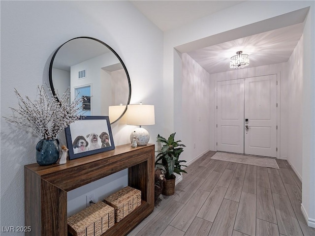 foyer featuring wood finished floors, visible vents, and baseboards