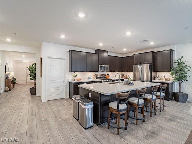 kitchen featuring a center island with sink, visible vents, appliances with stainless steel finishes, light countertops, and a sink