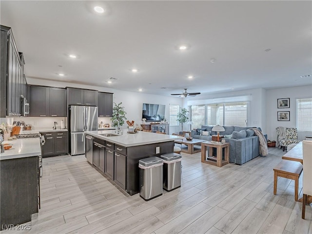 kitchen with light wood finished floors, stainless steel appliances, light countertops, open floor plan, and a sink