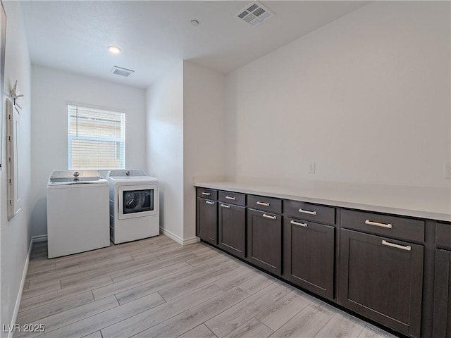 laundry area featuring light wood-type flooring, cabinet space, visible vents, and independent washer and dryer