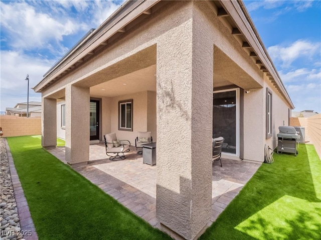 rear view of property with a patio, fence, and stucco siding