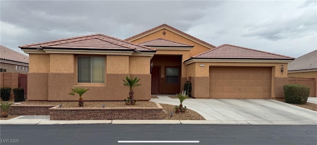 view of front facade featuring stucco siding, driveway, fence, an attached garage, and a tiled roof