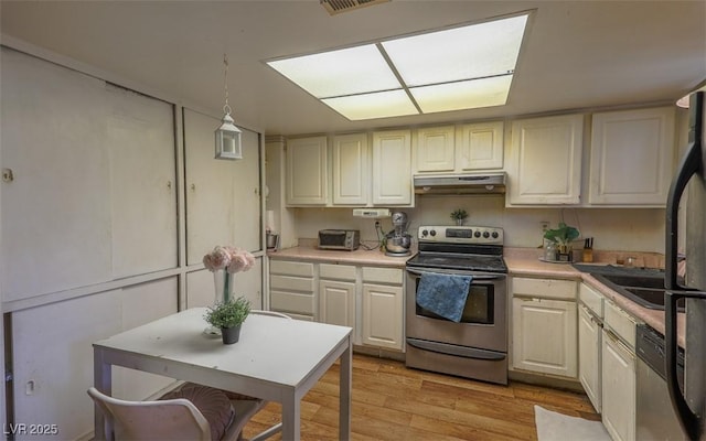 kitchen with under cabinet range hood, stainless steel appliances, light wood-style floors, and light countertops