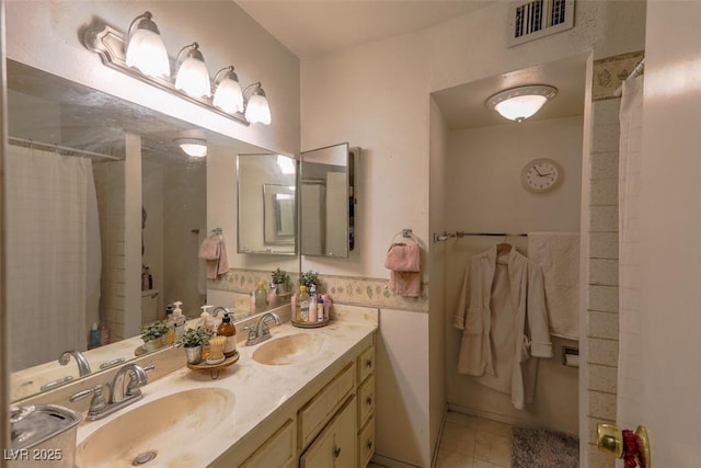 bathroom with double vanity, a sink, visible vents, and tile patterned floors