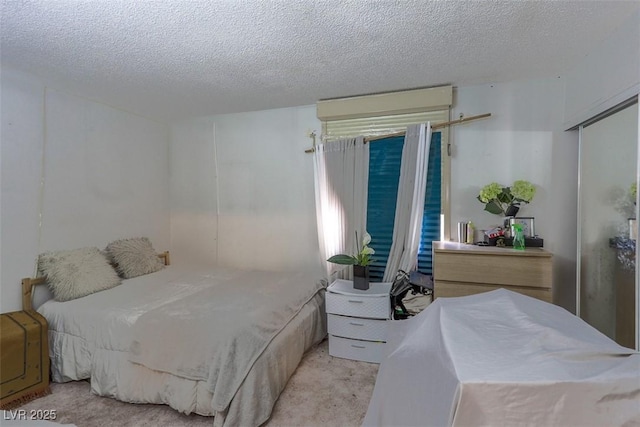 bedroom with a textured ceiling and light carpet