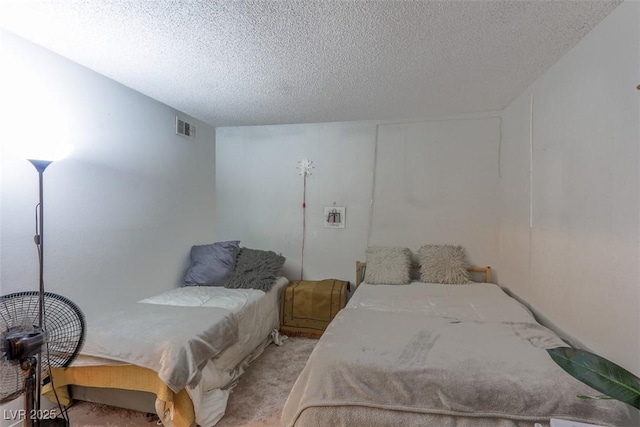 bedroom featuring light carpet, a textured ceiling, and visible vents