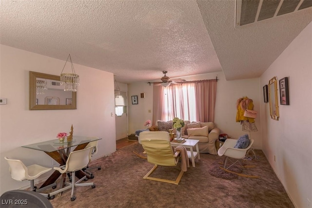 living room with a ceiling fan, carpet, visible vents, and a textured ceiling