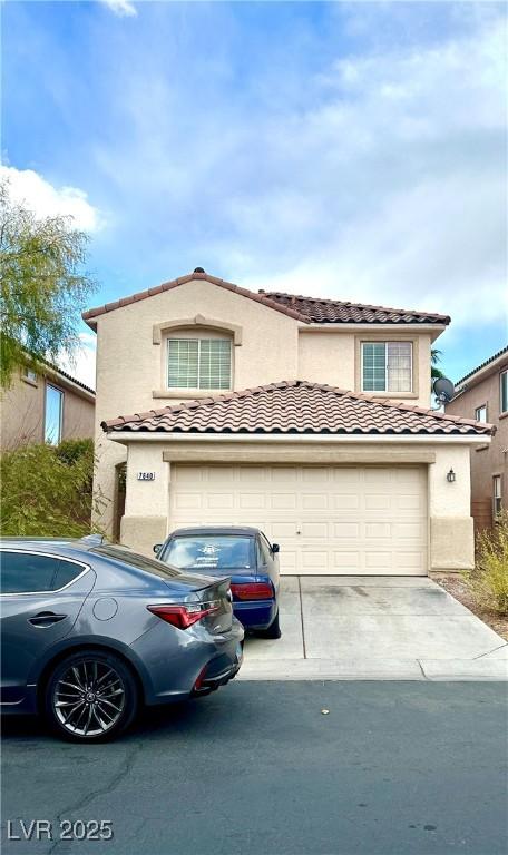 view of front facade with a garage, a tiled roof, concrete driveway, and stucco siding