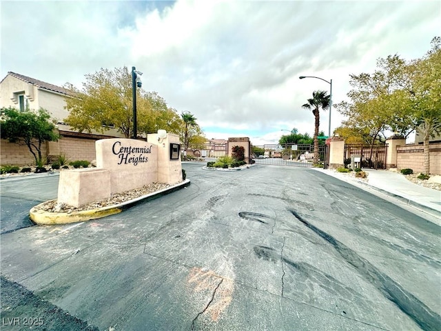 view of road featuring street lights, curbs, a gated entry, and a gate