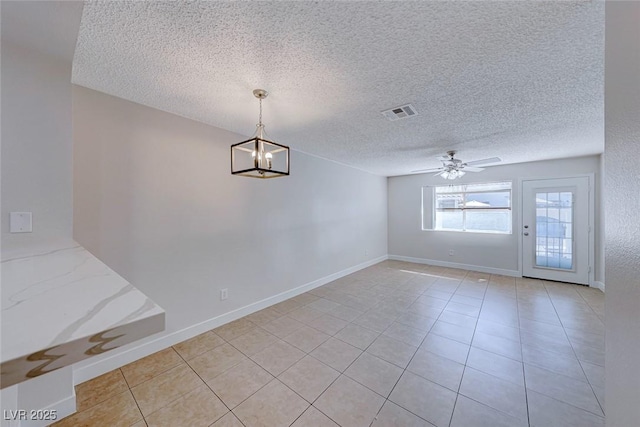 empty room featuring visible vents, light tile patterned flooring, a textured ceiling, baseboards, and ceiling fan with notable chandelier