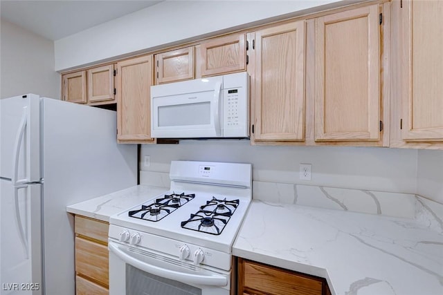 kitchen featuring light stone countertops, white appliances, and light brown cabinets