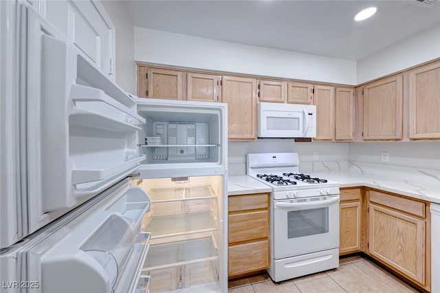 kitchen featuring light stone countertops, white appliances, light brown cabinets, and light tile patterned flooring