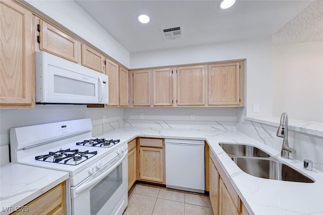 kitchen featuring recessed lighting, visible vents, light brown cabinetry, a sink, and white appliances