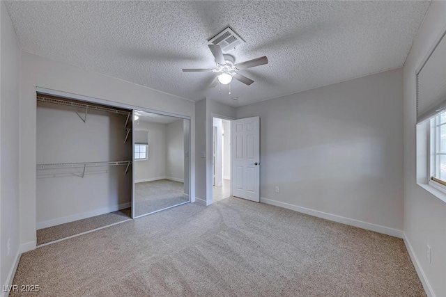 unfurnished bedroom featuring baseboards, visible vents, ceiling fan, carpet flooring, and a closet