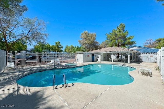 pool with a patio area, fence, and a hot tub