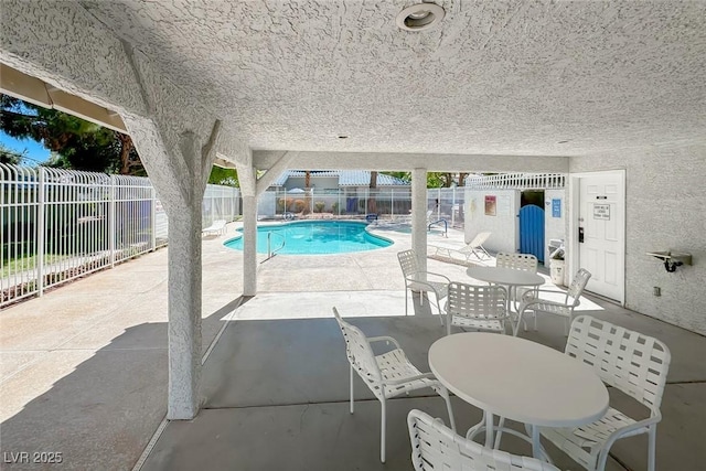 community pool with outdoor dining space, a patio area, and a fenced backyard