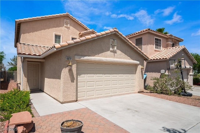 mediterranean / spanish-style house featuring a garage, driveway, a tiled roof, and stucco siding