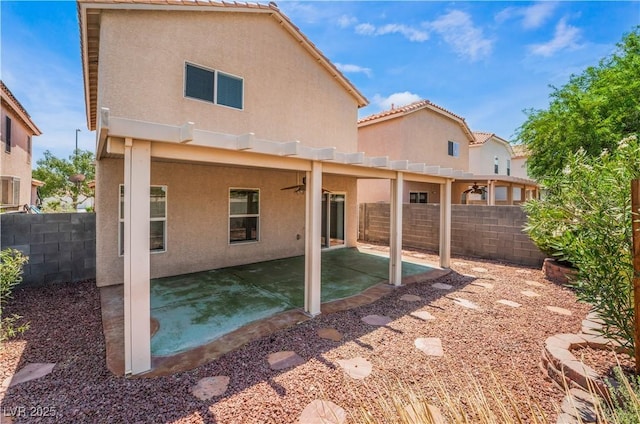 back of property featuring a fenced backyard, ceiling fan, and stucco siding