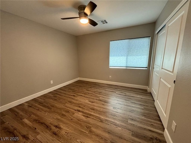 unfurnished bedroom featuring a closet, a ceiling fan, baseboards, visible vents, and dark wood-style flooring