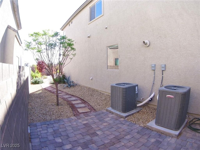 exterior space featuring stucco siding, fence, cooling unit, and a patio area