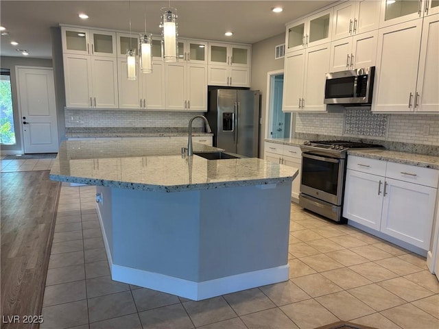 kitchen with a center island with sink, white cabinets, appliances with stainless steel finishes, and light tile patterned floors