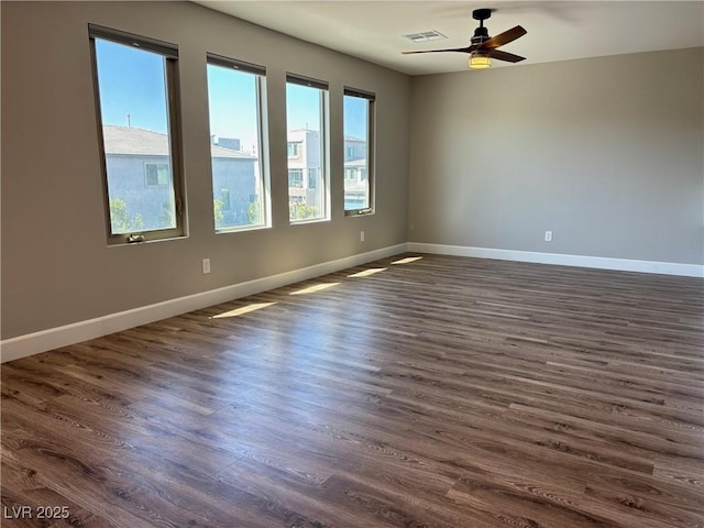 unfurnished room featuring dark wood-style floors, visible vents, ceiling fan, and baseboards