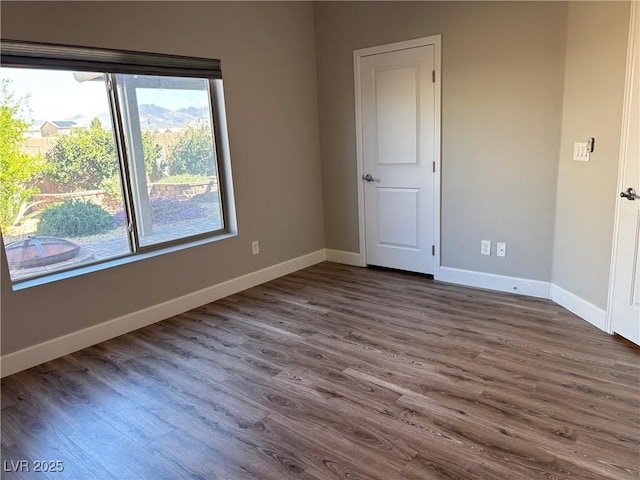 unfurnished room featuring baseboards and dark wood finished floors