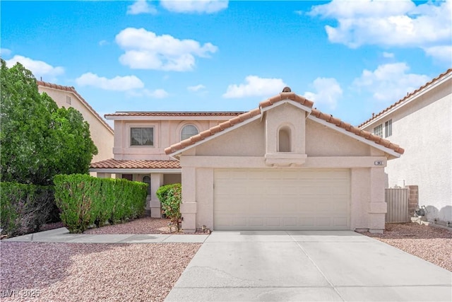 mediterranean / spanish-style home with a garage, a tiled roof, concrete driveway, and stucco siding