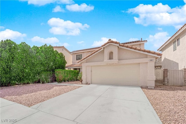 mediterranean / spanish house featuring a garage, concrete driveway, a tiled roof, a gate, and stucco siding